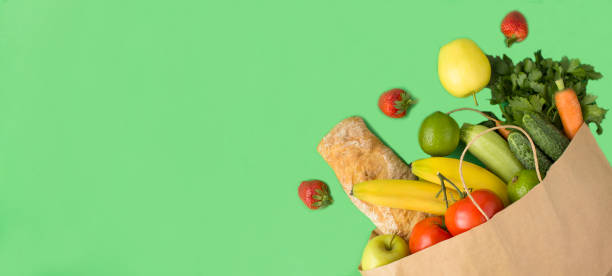 istock Paper bag with vegetable, fruit and baguette on the green background. Top view. Copy space. 1505155931