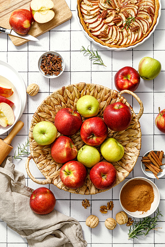 Apple. Fresh raw juicy red and green apples in a basket on a kitchen table with ingredients for cooking Thanksgiving autumn season apple pie, top view