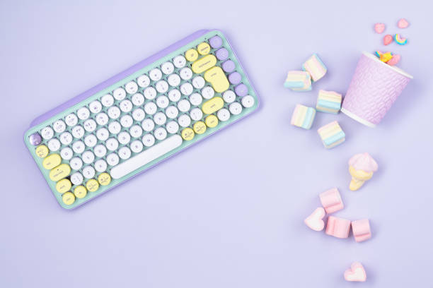 Pop keys and marshmallow with paper cup in pastel colors  on a lilac background. Workspace. Top view.