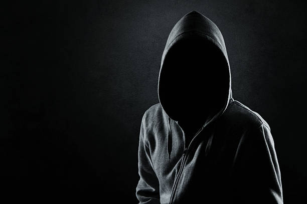 Man in the hood Silhouette of hooded man or hooligan over dark concrete background with copy space unrecognizable person stock pictures, royalty-free photos & images