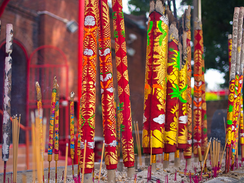 Sze Yup Temple, Glebe, Australia - January 17 2022 : Multiple colourful joss sticks ranging from large to small burns slowly at the front of the temple on a blurred background.