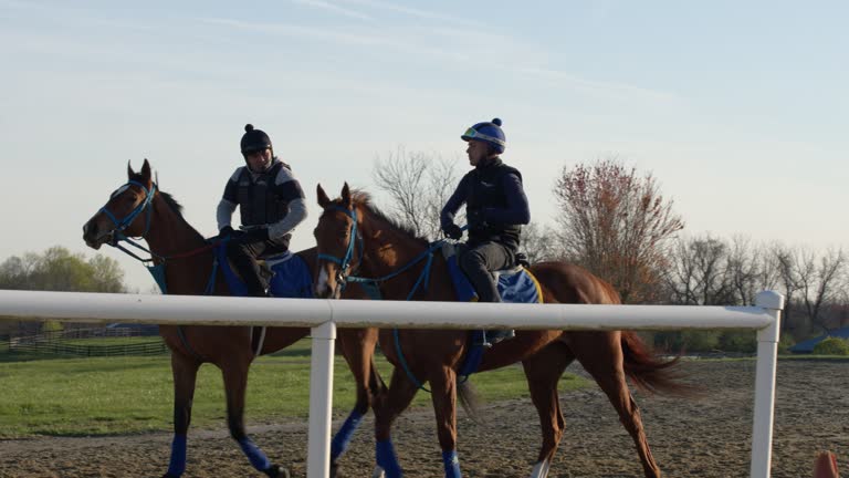 Heading to the Track: Jockeys Walking Race Horses to a Dirt Track Together for Training