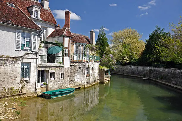 The beautiful town of Tonnerre in Burgundy ia famed for the Tonnerre Fosse, a natural eruption of water in the town which appears from underground, the water leave the town by the river in this image. The green balcony, umbrella, and boat all blend to make this a typical french scene