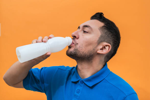 istock Handsome man drinks yogurt or milk on orange background. Mock up copy space 1505225914