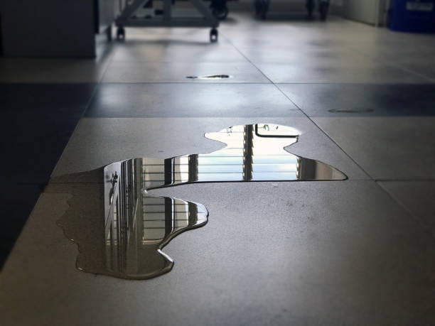water leak on the floor of building Close-up of spilled water leak on the floor of building. Wet floor from rainy splash or pipelines water leakage in office. Danger accident at home from liquid slippery floor hazard concept. floor length stock pictures, royalty-free photos & images