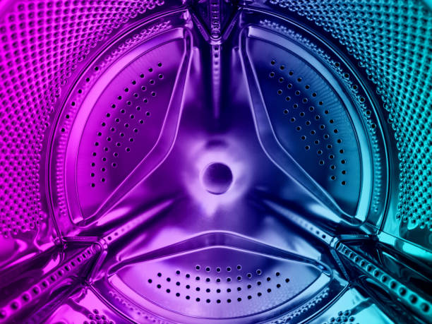 세탁기 드럼이 닫힙니다. 세�탁기 배경입니다. 세탁기 내부. 파란색과 분홍색 톤의 금속 세탁기 드럼. 구멍이 뚫린 반짝이는 금속 - clothes washer flash 뉴스 사진 이미지