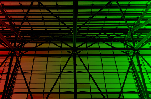 Lights and ventilation system in long line on ceiling of the  industrial building. Exhibition Hall in green and red tones. Ceiling factory construction
