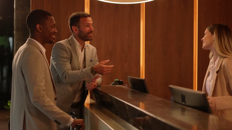 Female receptionist serving two guests and handing them their room key