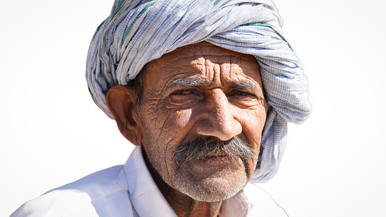 Shallow focus of an old Indian man wearing a turban, Amazed old Indian man wearing white turban looking at camera.