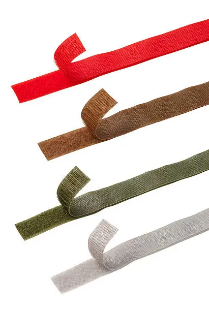 Four different color Velcro strips against white background. Red, brown green and gray color. Raised tape to show velcro system.