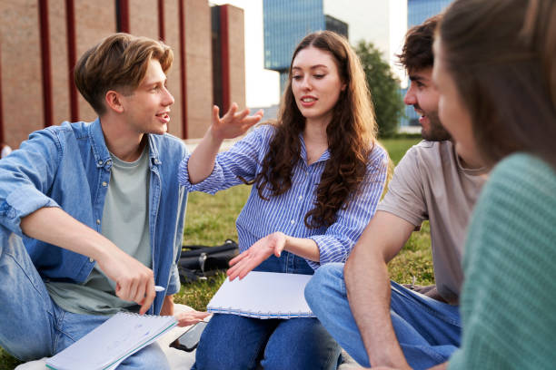 istock Group of caucasian students sitting outside the university campus and studying together 1505278430