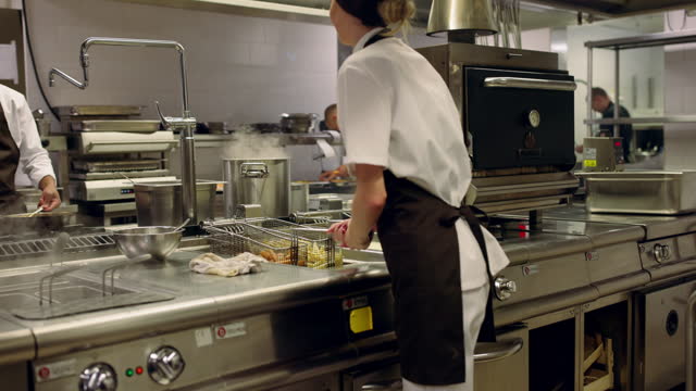 Chef frying and giving a shake to crispy fries in a hotel kitchen