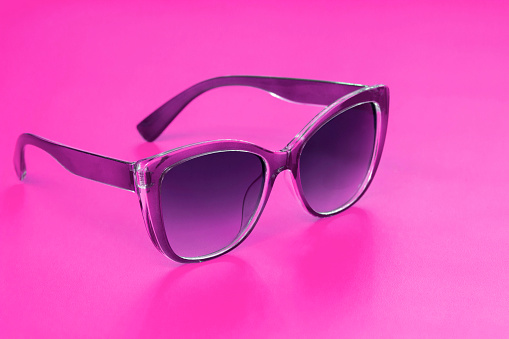 Modern fashionable sunglasses lying isolated on purple background. retro attribute concept