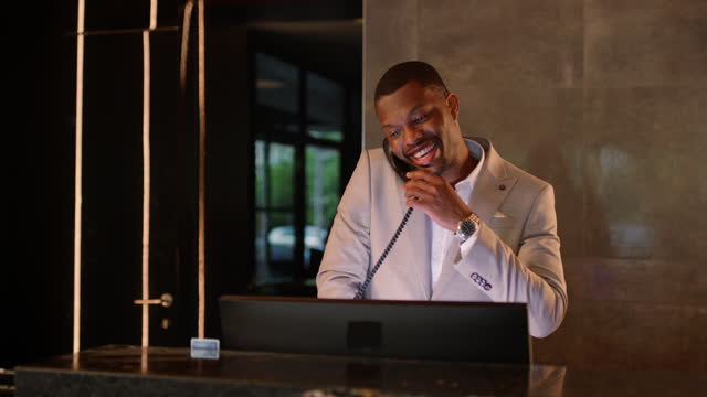 African-American hotel receptionist answering phone while working at helpdesk