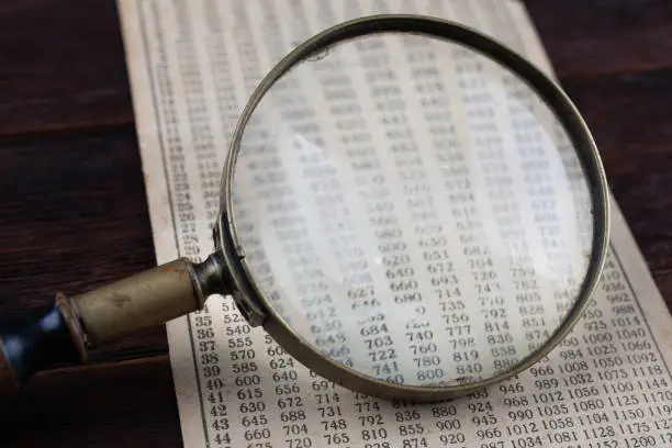 Photo of Retro cipher and cryptanalysis. Old vintage magnifying glass with calc table.