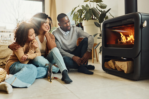 African American family relaxing by the fireplace in the living room. Copy space.