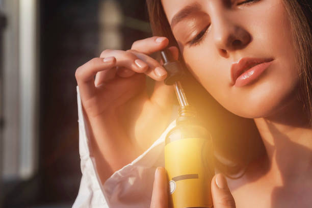 Close-up young cute woman with massage oil with pipette for face skin drops, thoughtful closed eyes. Lovely lady with cosmetic oil at window sunshine. Cosmetology self care concept. Copy ad text space primer plano joven linda mujer con aceite de masaje con pipeta para gotas de piel facial, ojos cerrados pensativos. señora encantadora con aceite cosmético a la luz del sol de la ventana. concepto de autocuidado de cosmetología. copiar el espacio de tex