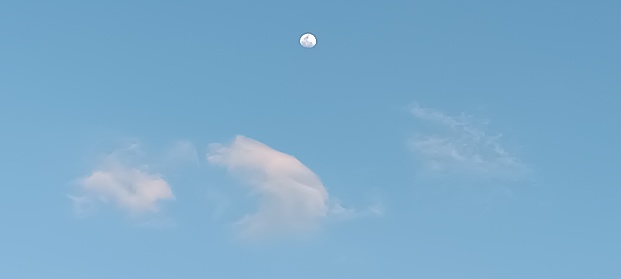 The moon is appear at the afternoon blue sky