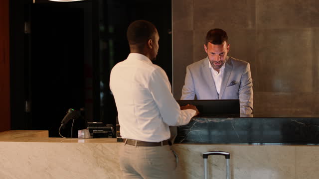 African-American businessman talking with hotel receptionist while booking room