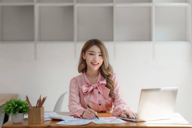 istock Smiling Asian Accountant person analyze financial report and studies annual figures, analyzes profits 1505333732