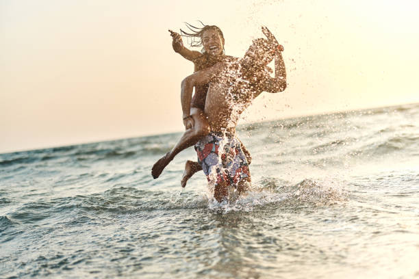 istock Cheerful couple having fun while splashing and piggybacking at sea. 1505339723