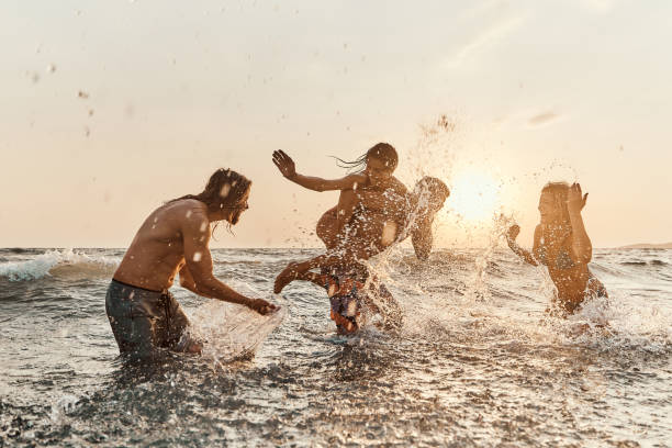 istock Carefree friends having fun while playing in sea at sunset. 1505344080