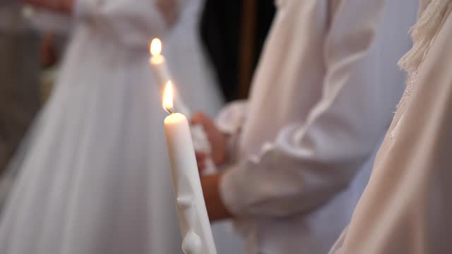 During the liturgy dedicated to the First Holy Communion of children, a boy holds a burning candle in his hands. Symbol of Holy Communion.