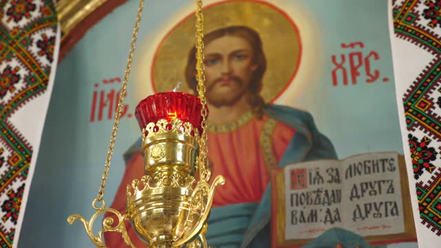 A burning lamp against the background of the icon of Jesus Christ with the commandments of God.