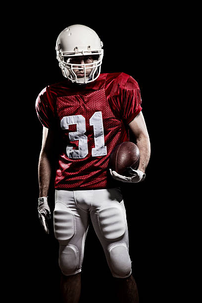 Football Player with number Football Player with number on the red uniform and a ball in the hand. Studio shot. american football player studio stock pictures, royalty-free photos & images