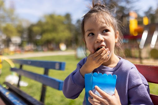 Little girl eating popcorn in a public park