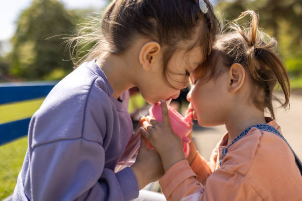 Japanese little girls drinking water from the same bottle in a public park