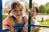 Portrait of little girl on a jungle gym with her mother