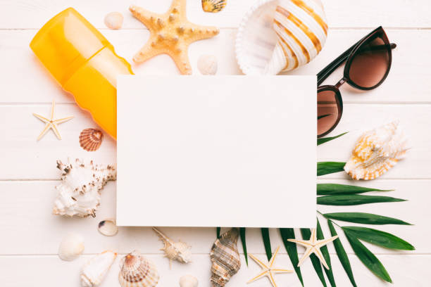 istock Summer time concept with blank greeting card and blank white paper on colored background. Seashells from ocean shore in the shape of frame separated with space for text top view 1505407170