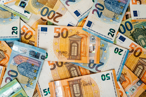 Heap of assorted colorful EURO bills laid down on a flat surface. Focus on a fifty Euro bill.