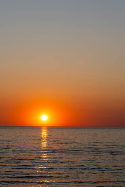 istock A large orange sun setting over a calm sea. 1505413331