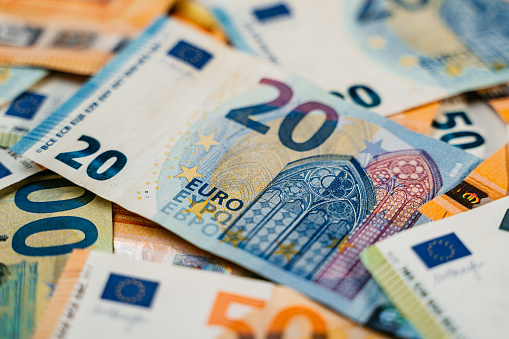 Heap of assorted colorful EURO bills laid down on a flat surface. Focus on a twenty Euro bill.