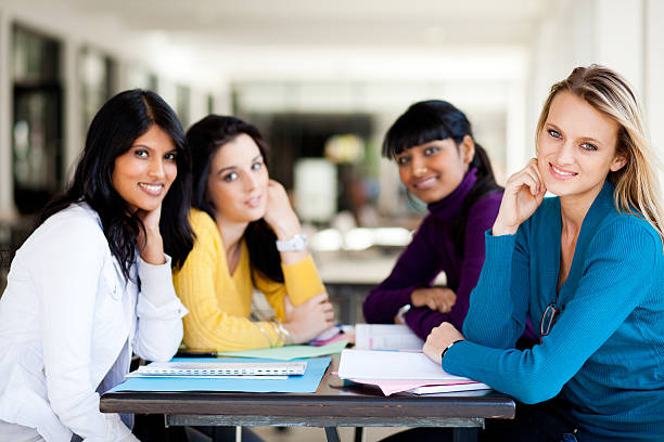 Young female students sharing a book in library