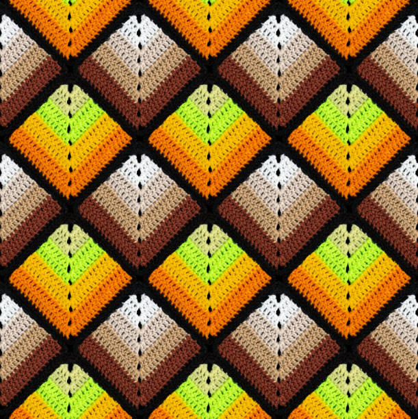 Seamless knitted pattern in the form of gradient rhombuses is crocheted with multi-colored threads. Patchwork style. Acrylic blanket.