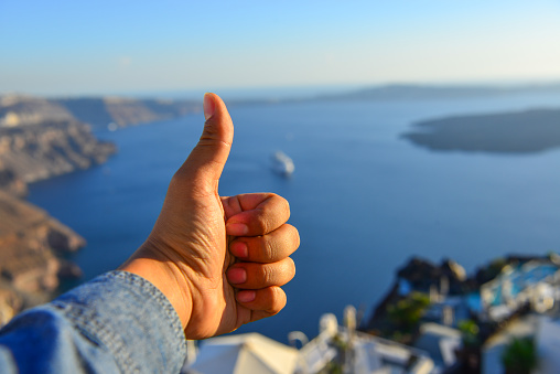 Male hand with seascape of Santorini Island in sunny day.