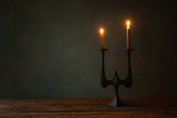 burning candles in vintage candlesticks on dark background