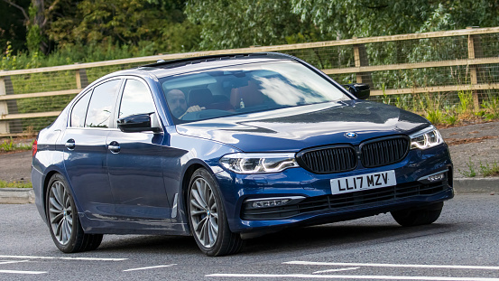 Milton Keynes,UK - June 24th 2023. 2017 blue BMW 5 SERIES 540I XDRIVE SE AUTO travelling on an English country road