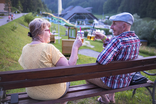 Senior couple having a drink on the bench at the Resort they are staying for their anniversary