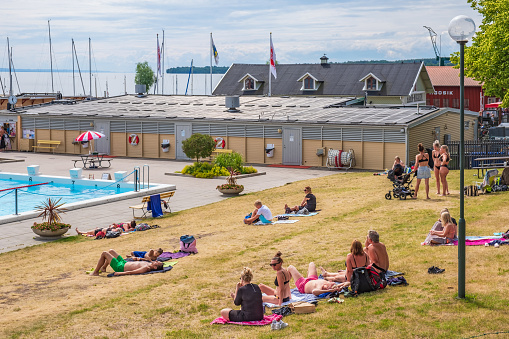 Hjo, Sweden-July, 2020: Bathing place with sunbathing people at the city Hjo in Sweden