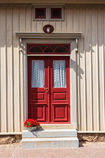 Red door on an old house with a flower pot