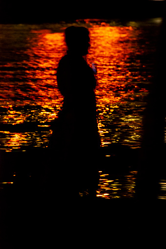 Silhouette woman and the sea at night with colorful lights