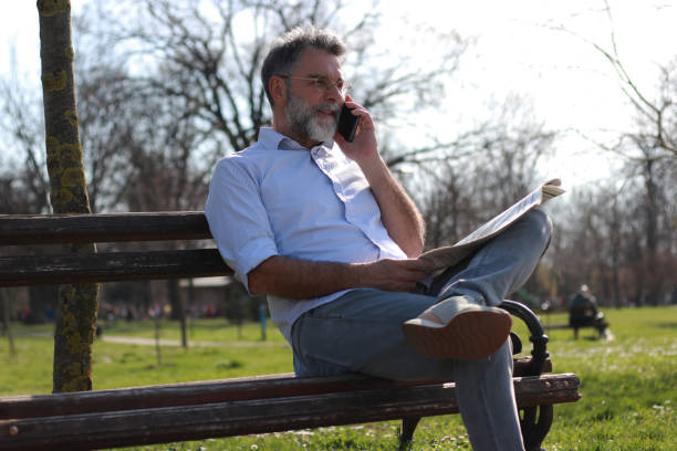 istock Mature man sitting on bench read newspaper 1505566520