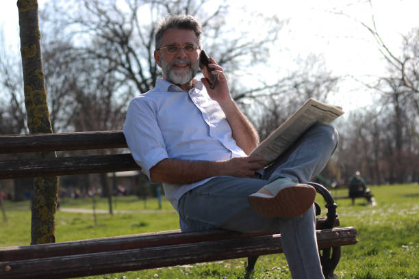 istock Mature man sitting on bench read newspaper 1505566549