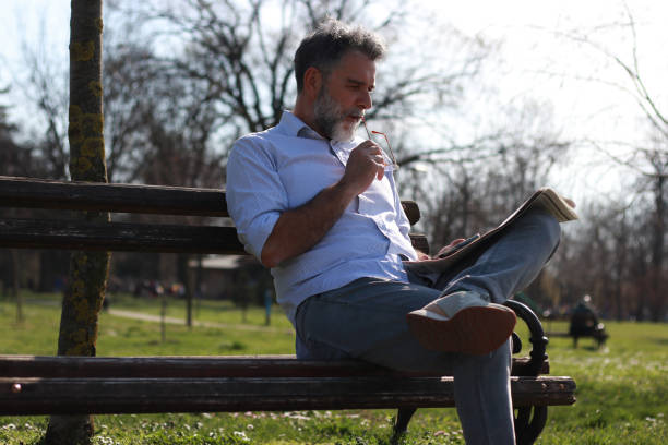 istock Mature man sitting on bench read newspaper 1505567122