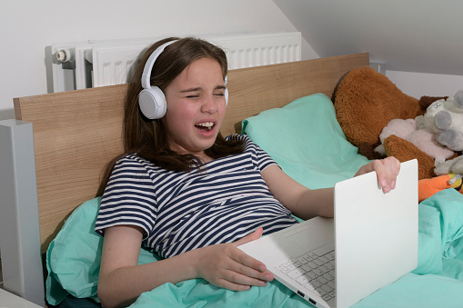 Girl schoolgirl in a bad mood with a computer in bed. Falling asleep, shutting down the computer