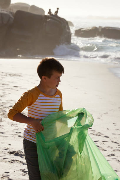 istock Cute lonely boy cleaning the beach 1505586624